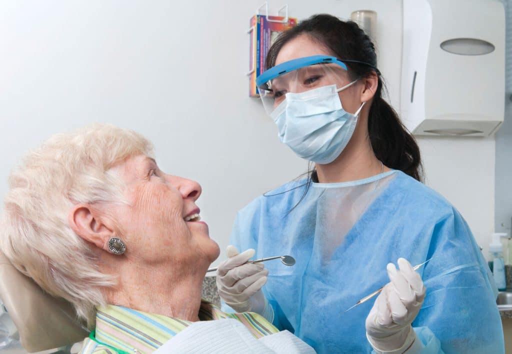 a mature patient in a dental chair smiles at the dentist
